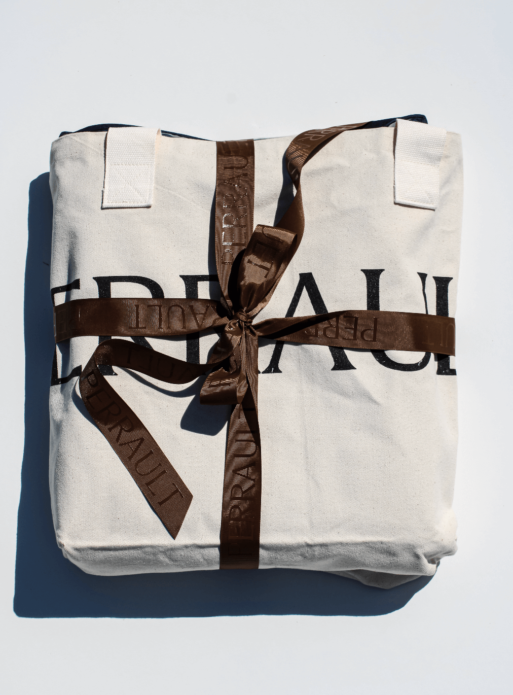 Perrault tote bag with brown ribbon around it