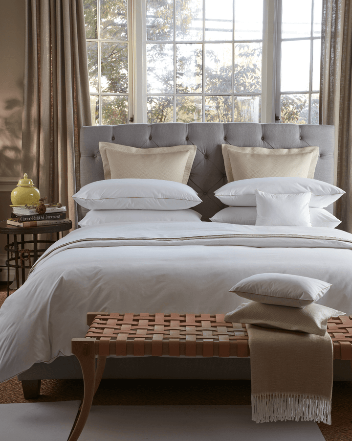 Bed beside a window with a Matouk Pezzo Throw in Champagne folded at the end