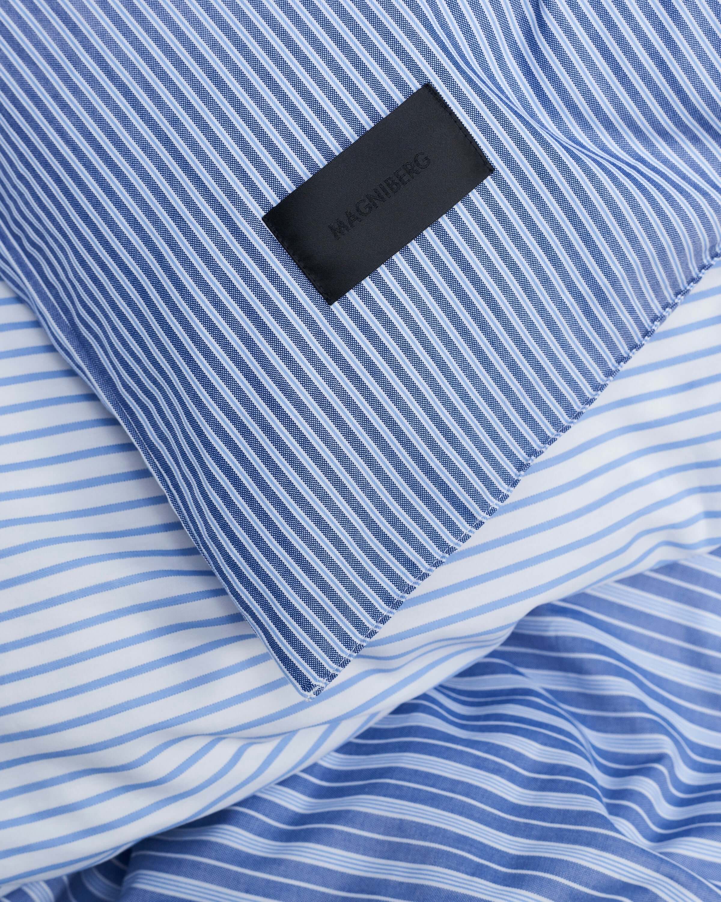 Close up of the Magniberg Wall Street bedding with black Magniberg label and various stripes