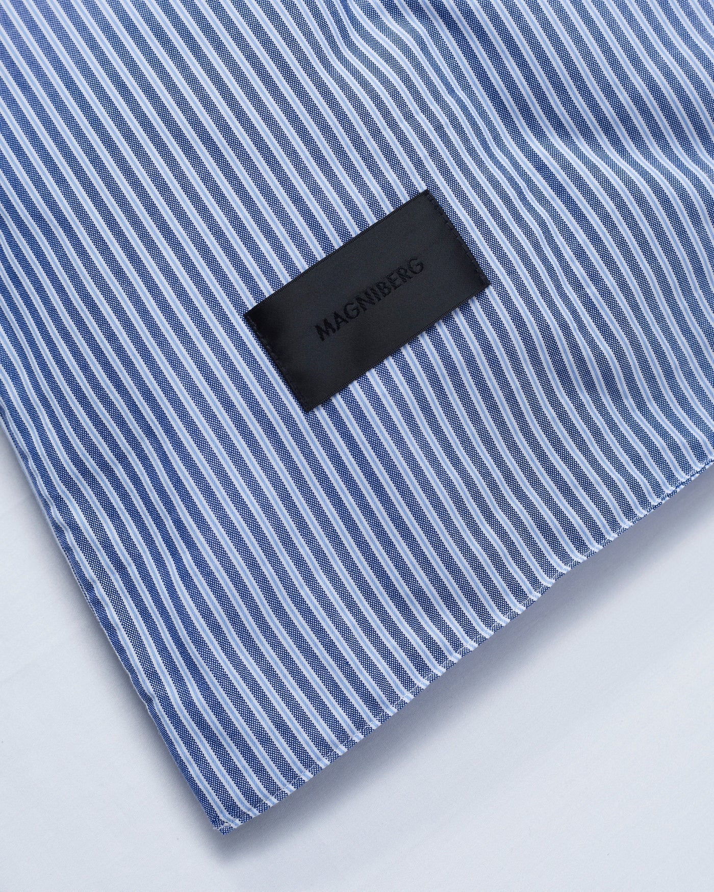 Corner of the Magniberg Wall Street pillowcase in dark stripe