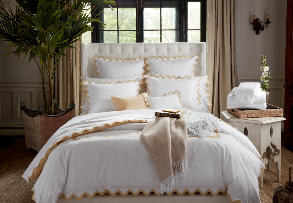 Matouk Pezzo throw in Champagne lying at the end of a bed in a opulent bedroom