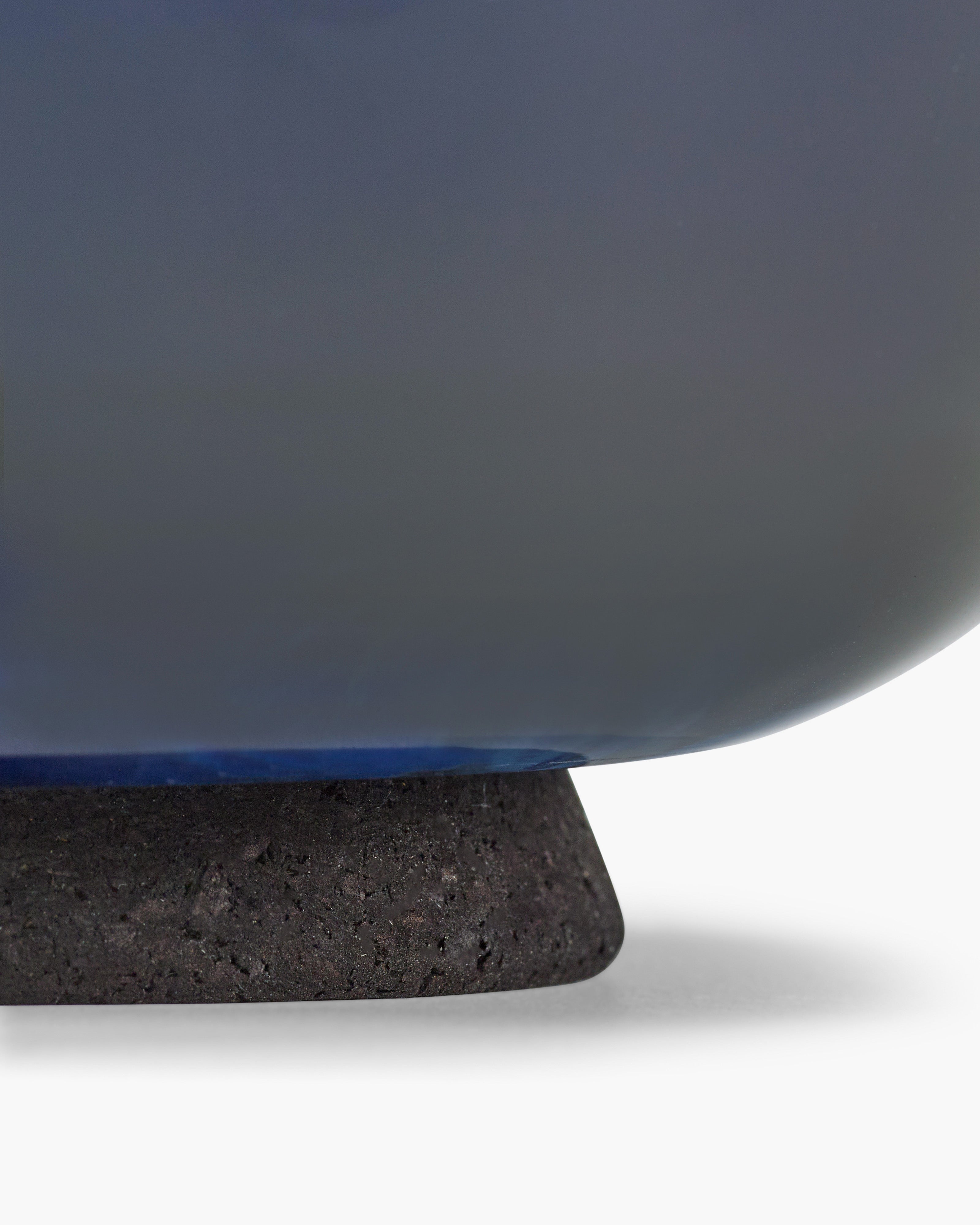 Close-up of a blue ceramic vase with a dark brown base on a white background