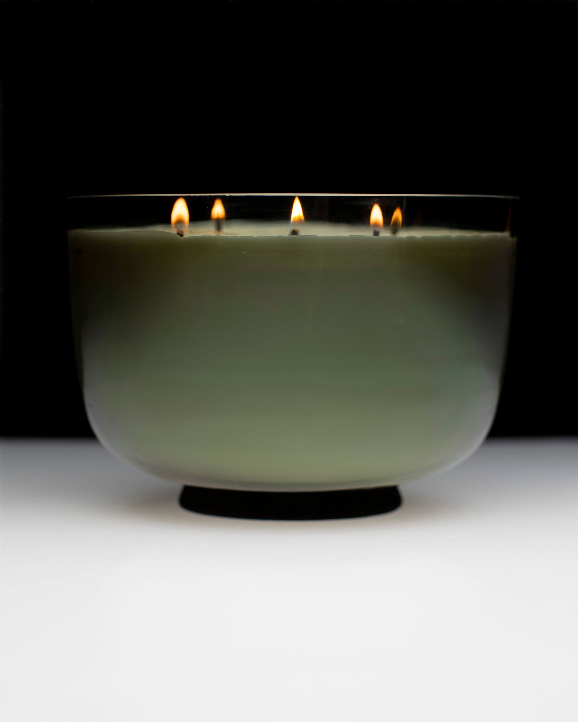 Candle in a glass holder with multiple wicks on a black background
