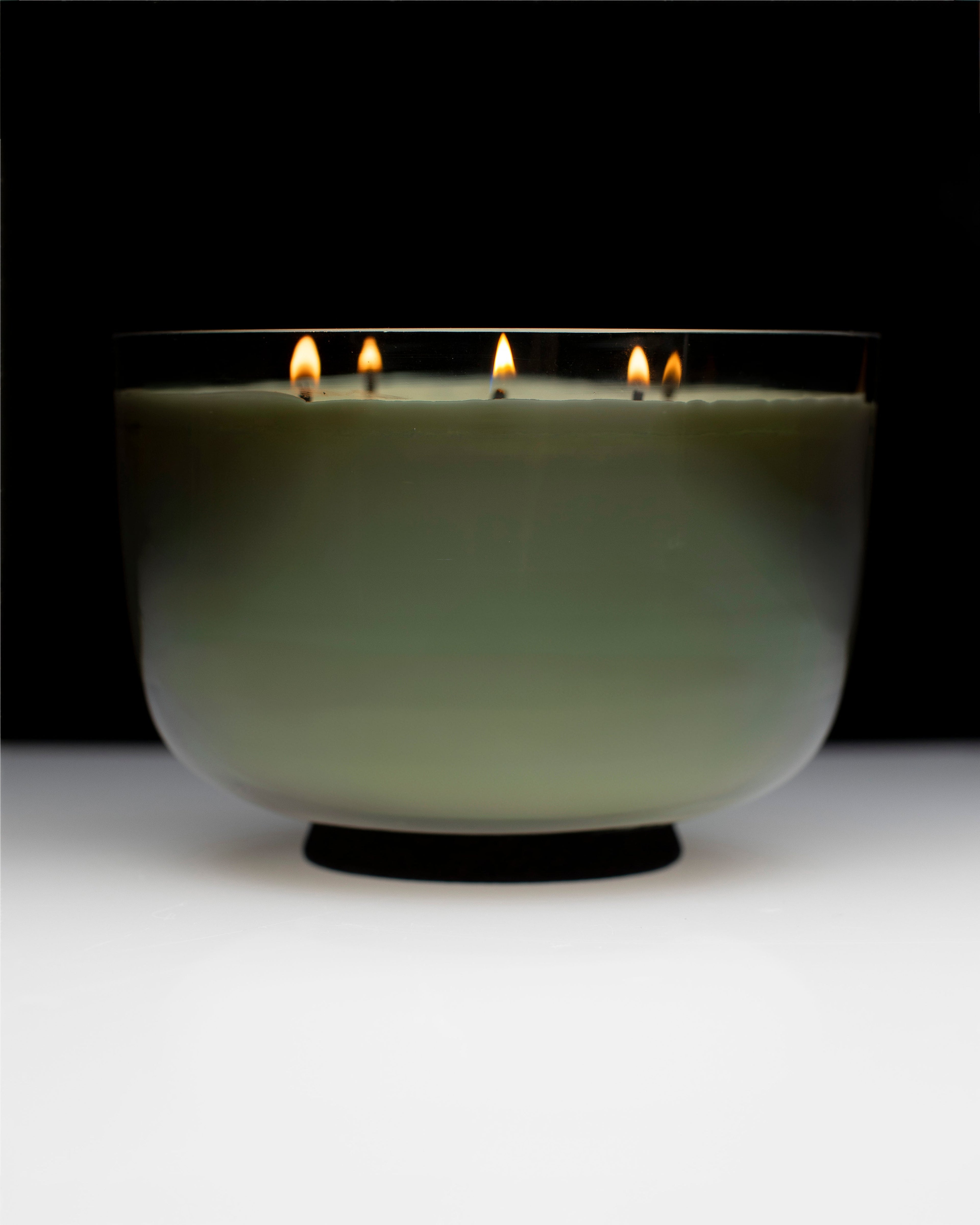 Candle in a glass holder with multiple wicks on a black background