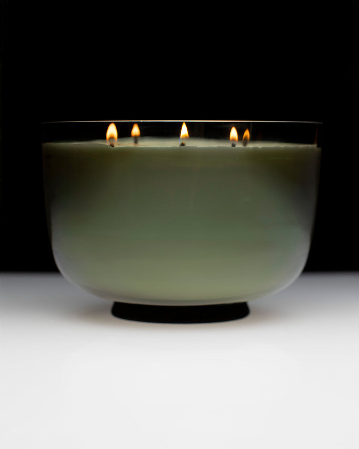 Candle in a glass holder with multiple wicks on a black background