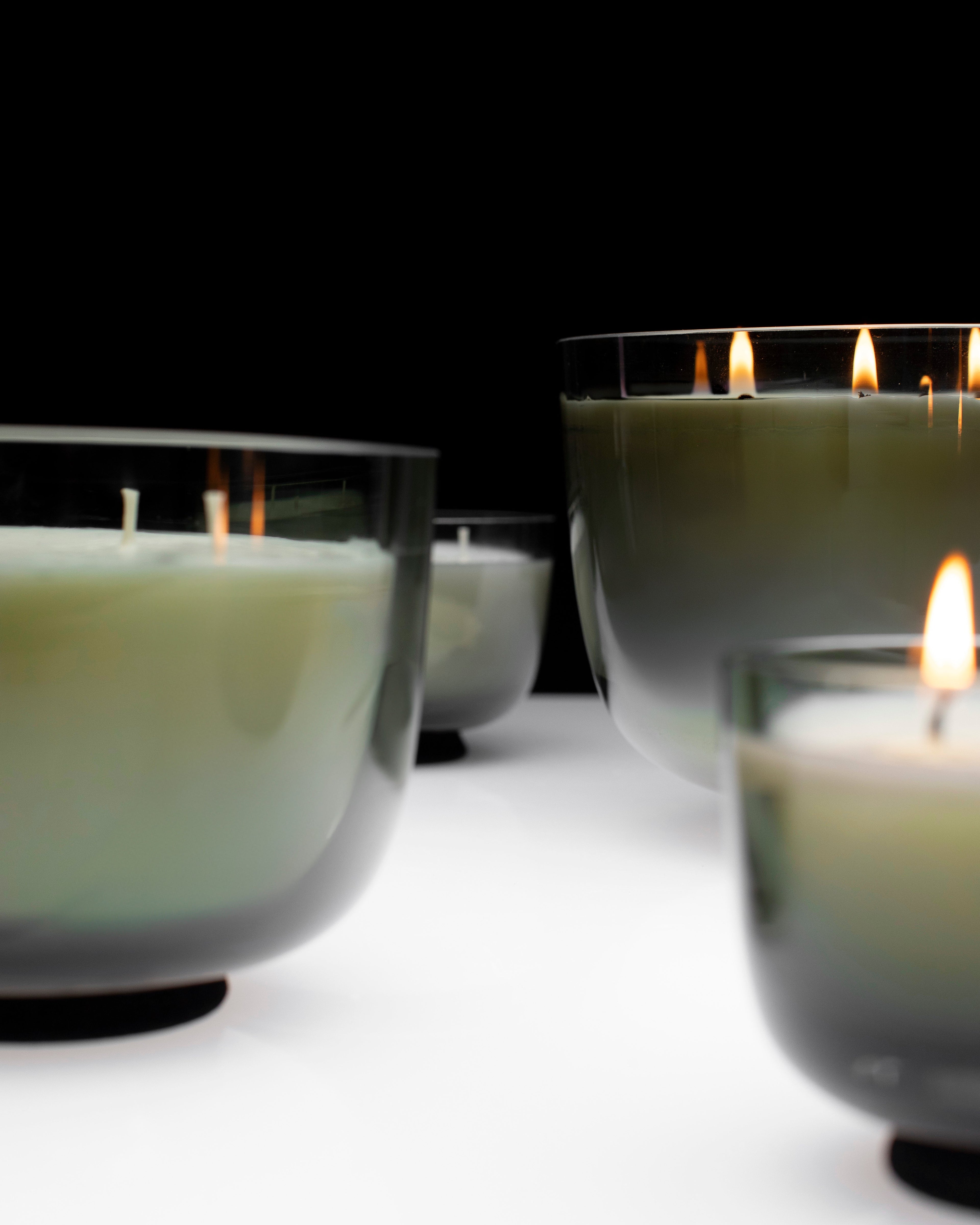 Candle holders with lit candles on a dark background serax vincent van duysen