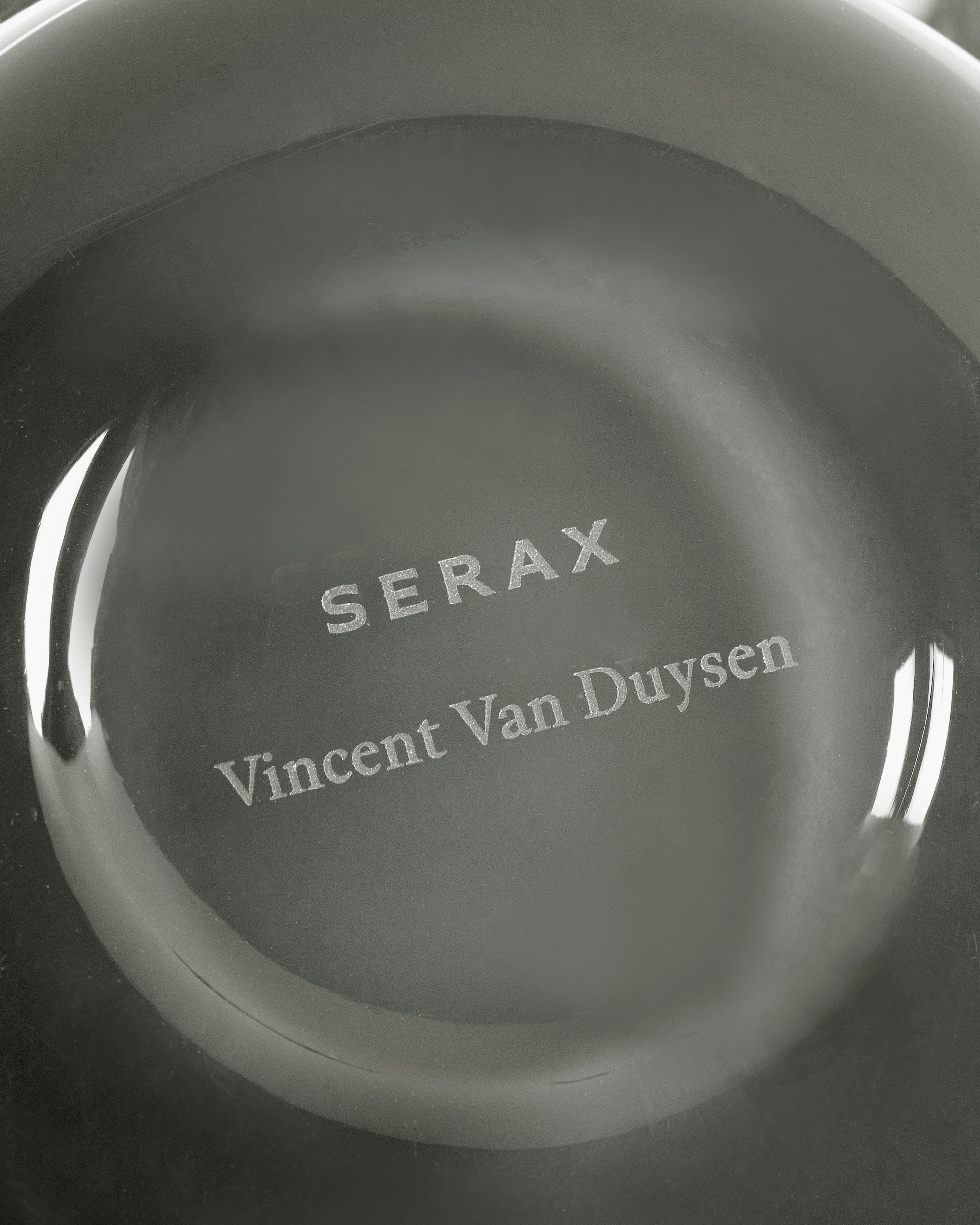 Gray dish with 'SERAX Vincent Van Duysen' engraved on a white background candle