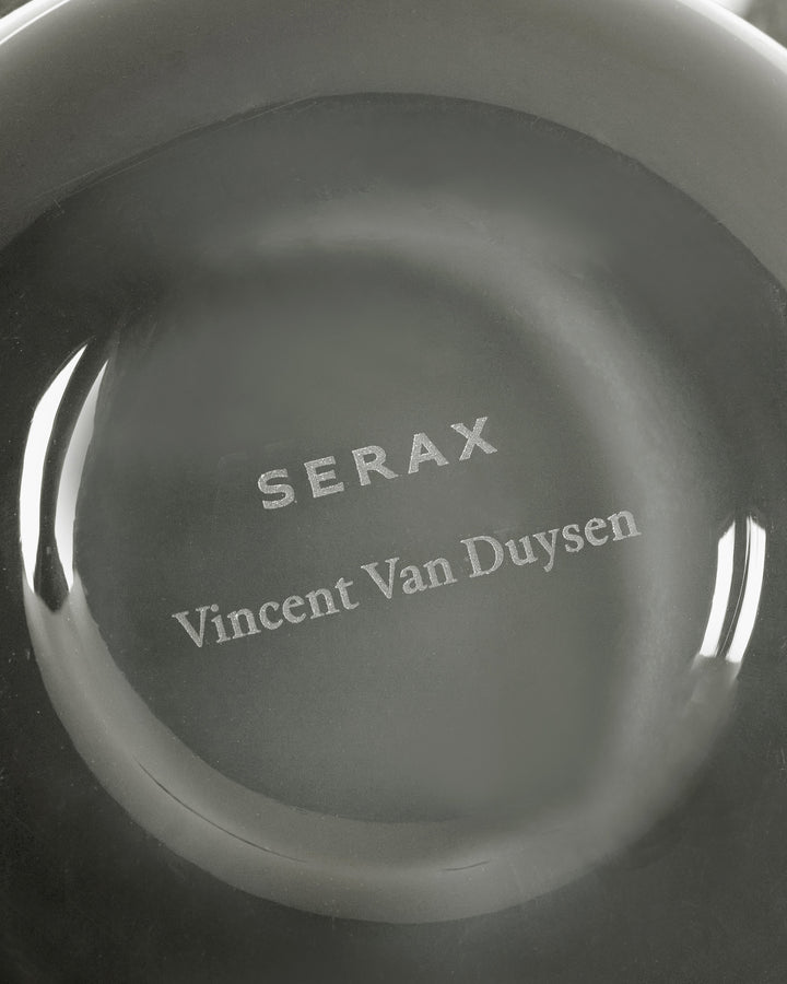 Gray dish with 'SERAX Vincent Van Duysen' engraved on a white background candle