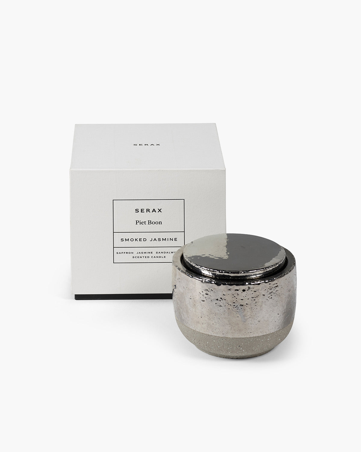 Silver candle with a black lid and packaging labeled 'Serax' on a white background
