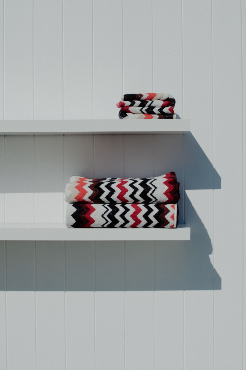 Patterned towels on white shelves against a light gray wall