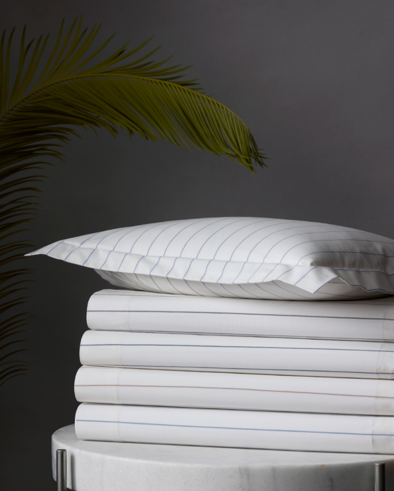 A stack of Matouk Amalfi Striped Sheets 